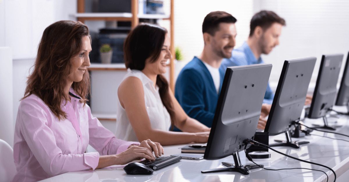 Personas sonriendo y trabajando en ordenadores, backups o copia de seguridad.