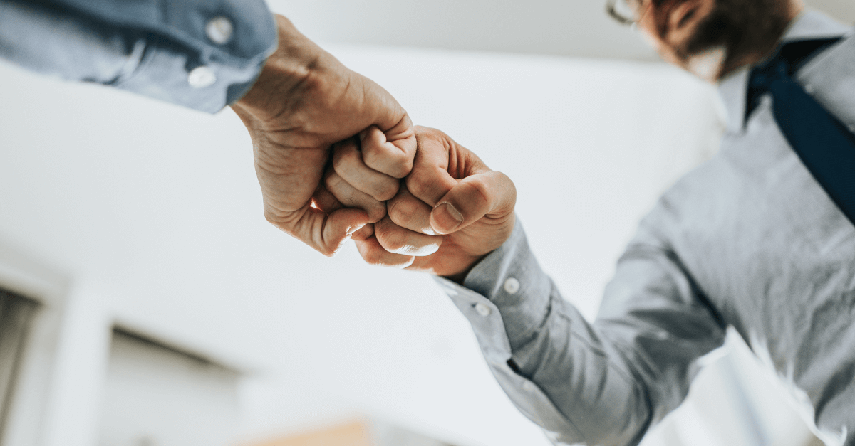 Dos personas chocando puños, colaboración entre equipos de ciberseguridad.