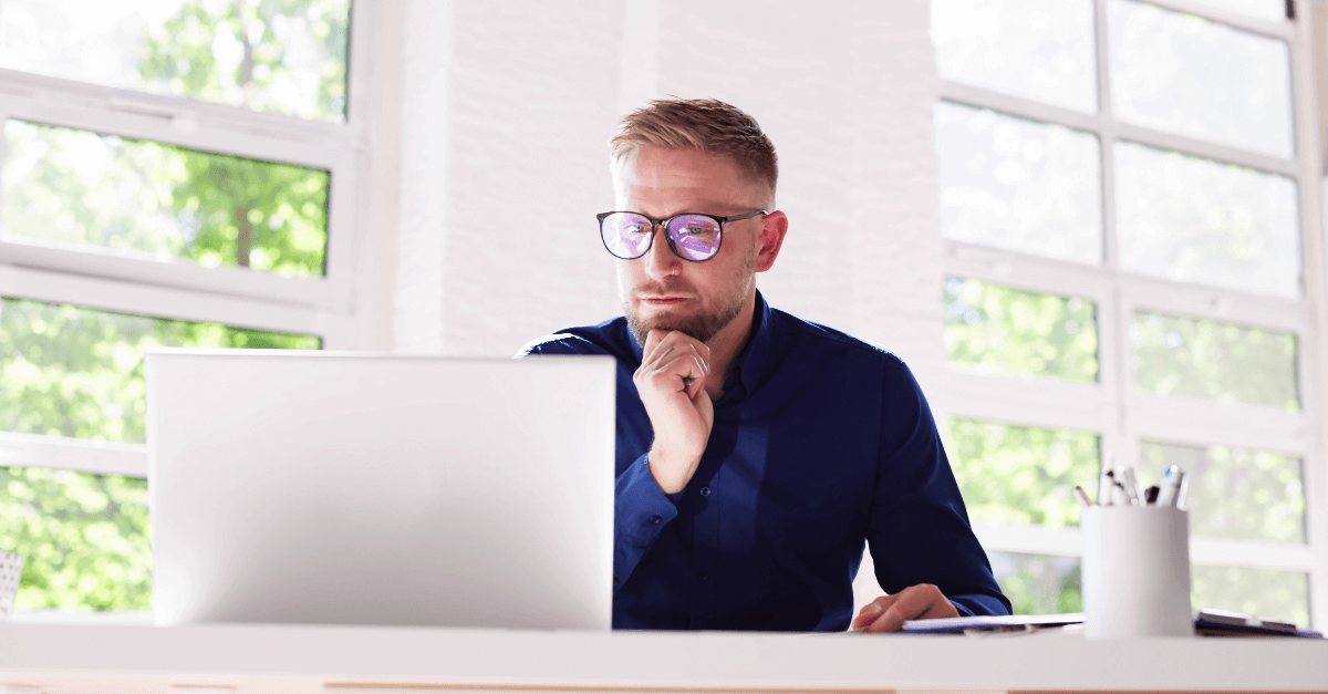Un hombre con gafas lee en su portátil, ataques cibernéticos