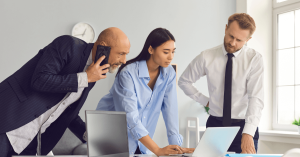 dos chicos y una chica frente a un ordenador portátil en una oficina reunidos por la brecha digital